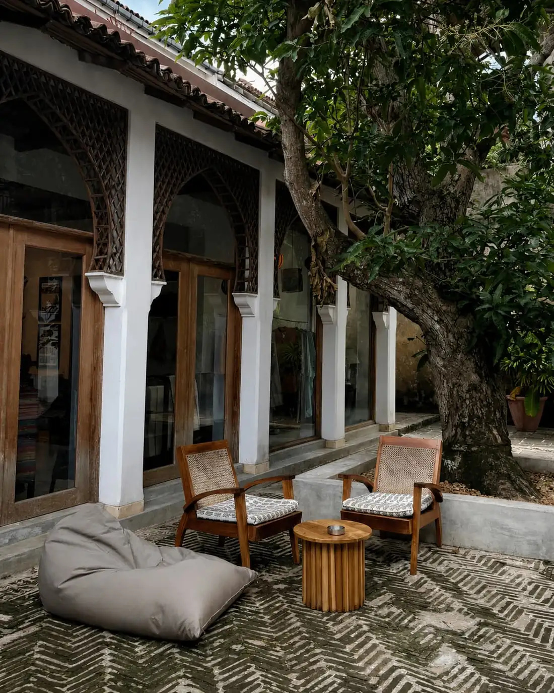 Rattan chairs and a bean bag on zigzag brick under the tree in the Kaffi Galle Fort courtyard.