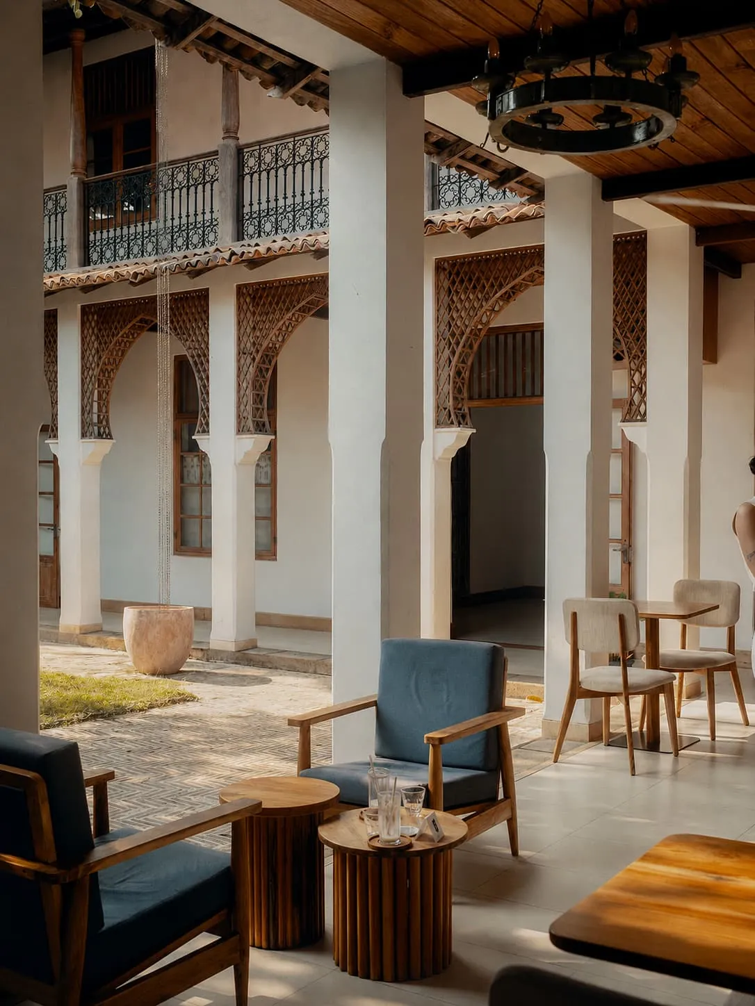Blue upholstered armchairs and fluted timber side tables under the colonnade.
