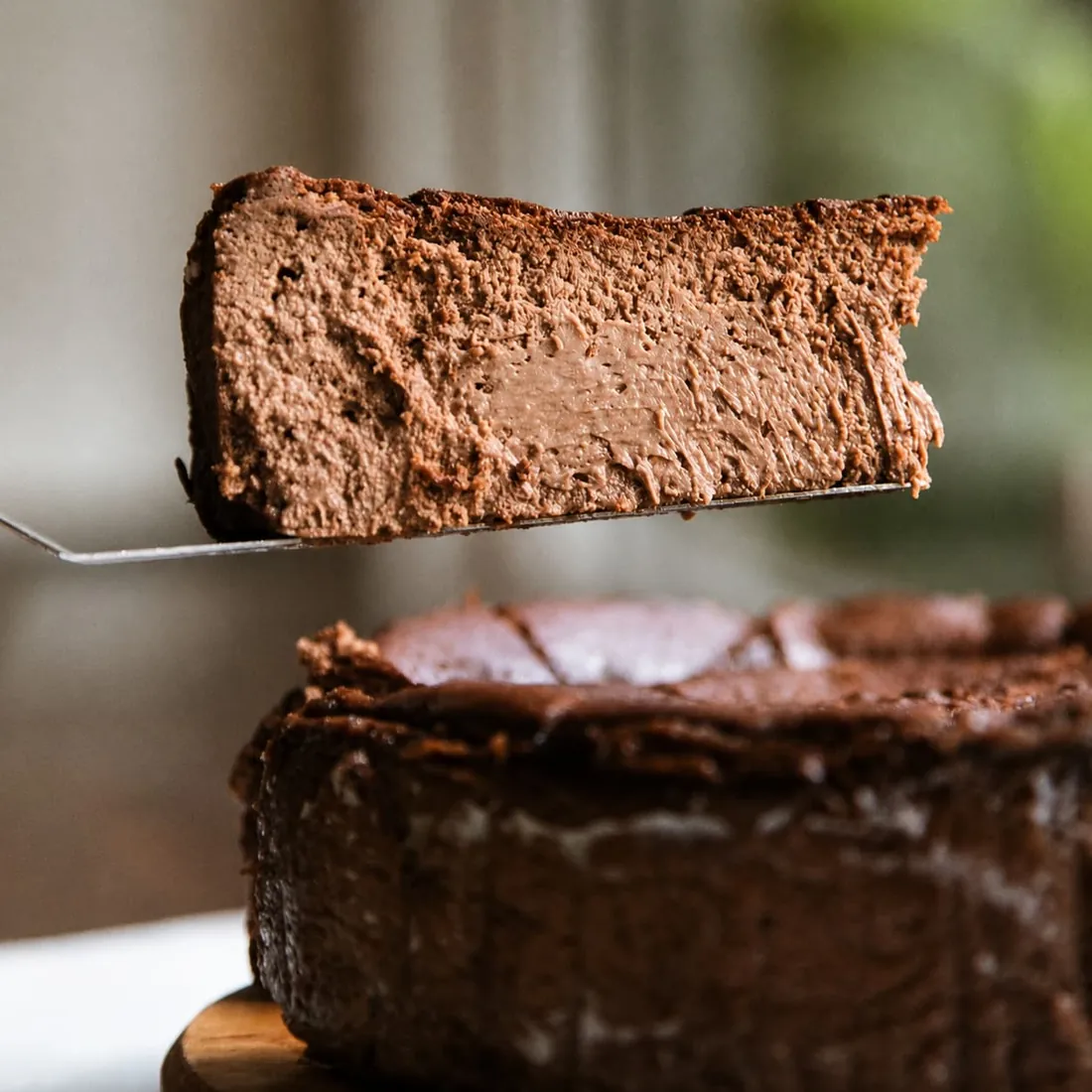A slice of chocolate cheesecake lifted from the whole cake.
